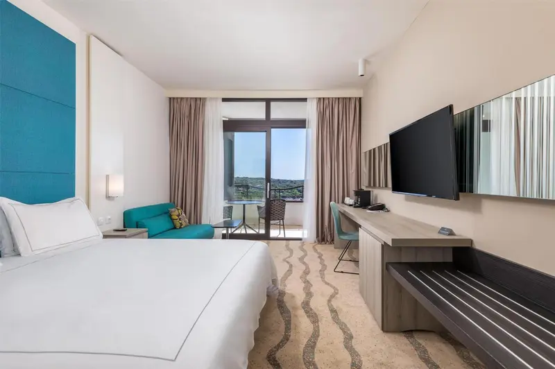 Chambre lumineuse avec un lit blanc et un espace détente.
