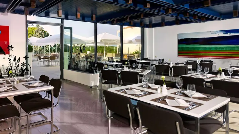Une salle de restaurant lumineuse avec des tables dressées et une vue sur une terrasse.