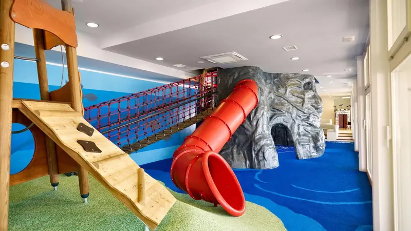 Espace de jeux intérieur avec toboggan et structure d'escalade.