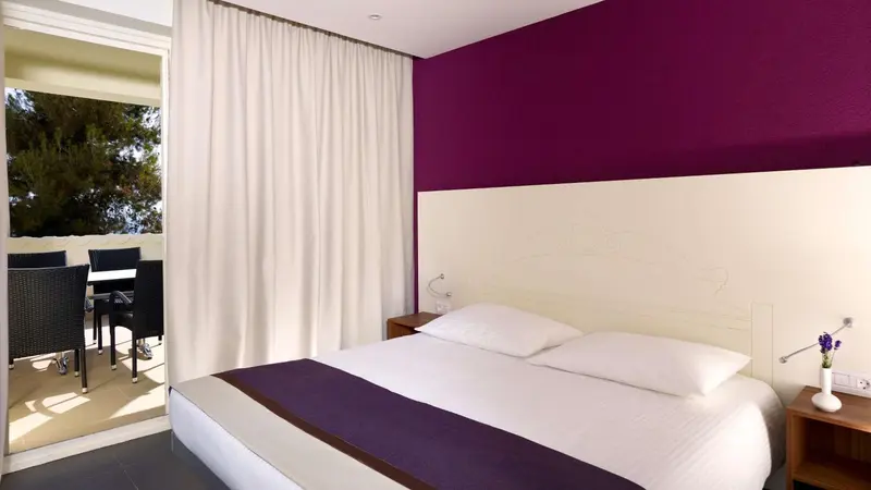 Une chambre lumineuse avec un lit double et un accès à une terrasse.