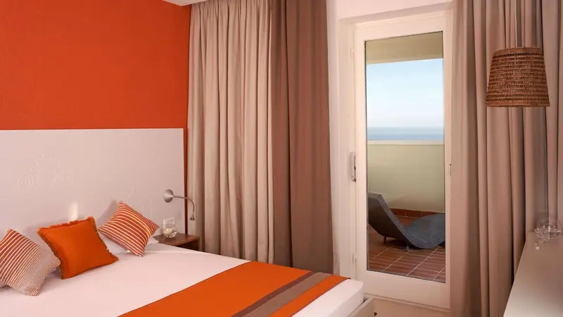 Une chambre lumineuse avec un lit double et un accès à une terrasse.