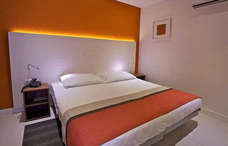 Une chambre lumineuse avec un grand lit recouvert d'une couverture colorée.