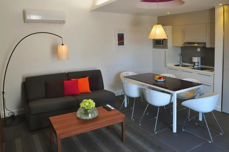 Un espace de vie intérieur moderne avec un canapé, une table à manger et une kitchenette.