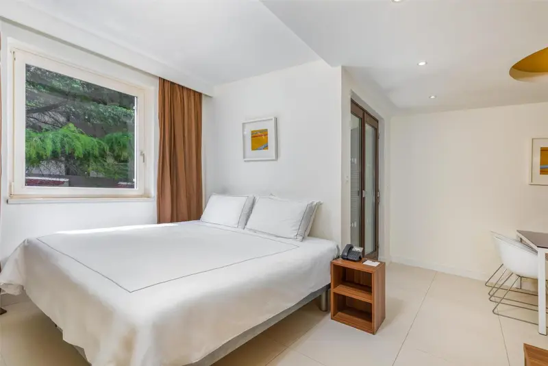 Une chambre lumineuse avec un lit blanc et une fenêtre.