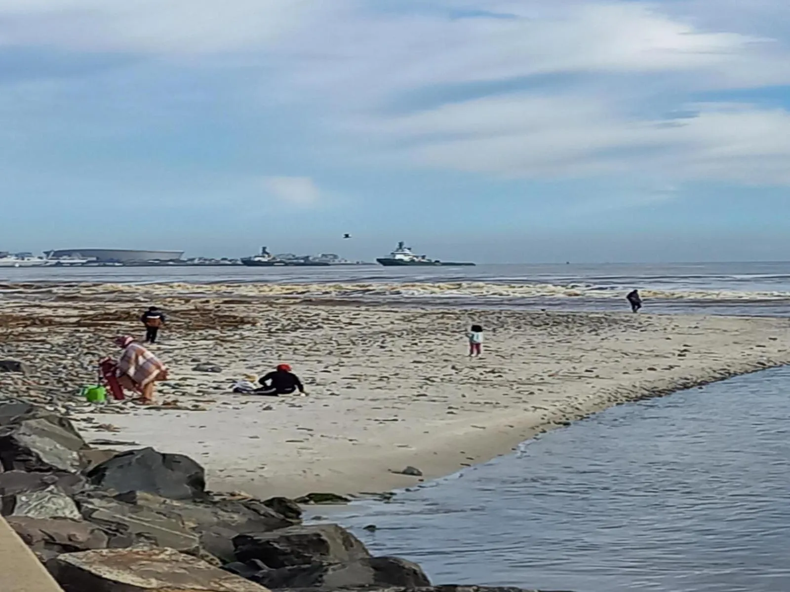 Une plage de sable avec des personnes se promenant et jouant près de l'eau.