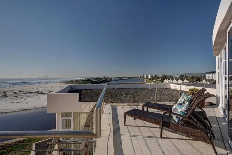 Terrasse avec mobilier d'extérieur donnant sur une plage et une ville côtière.