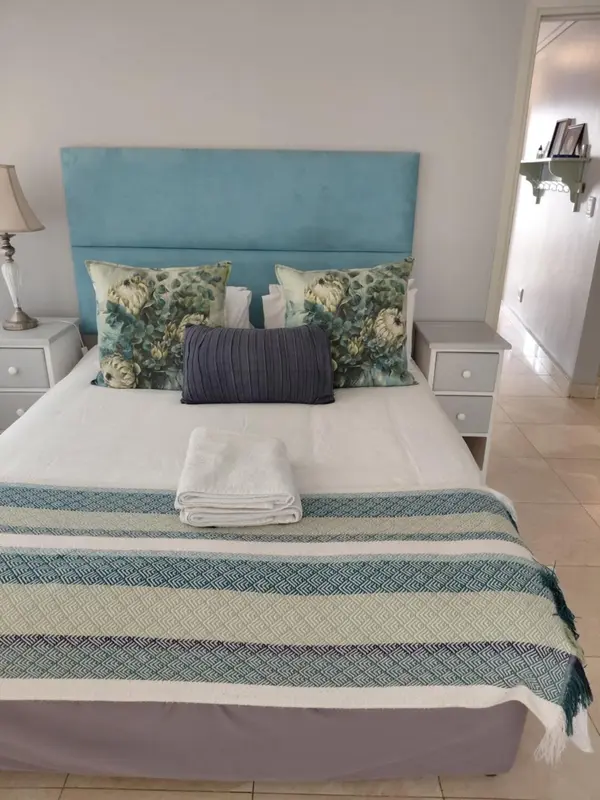 Une chambre avec un grand lit recouvert d'une couverture à motifs et de coussins.
