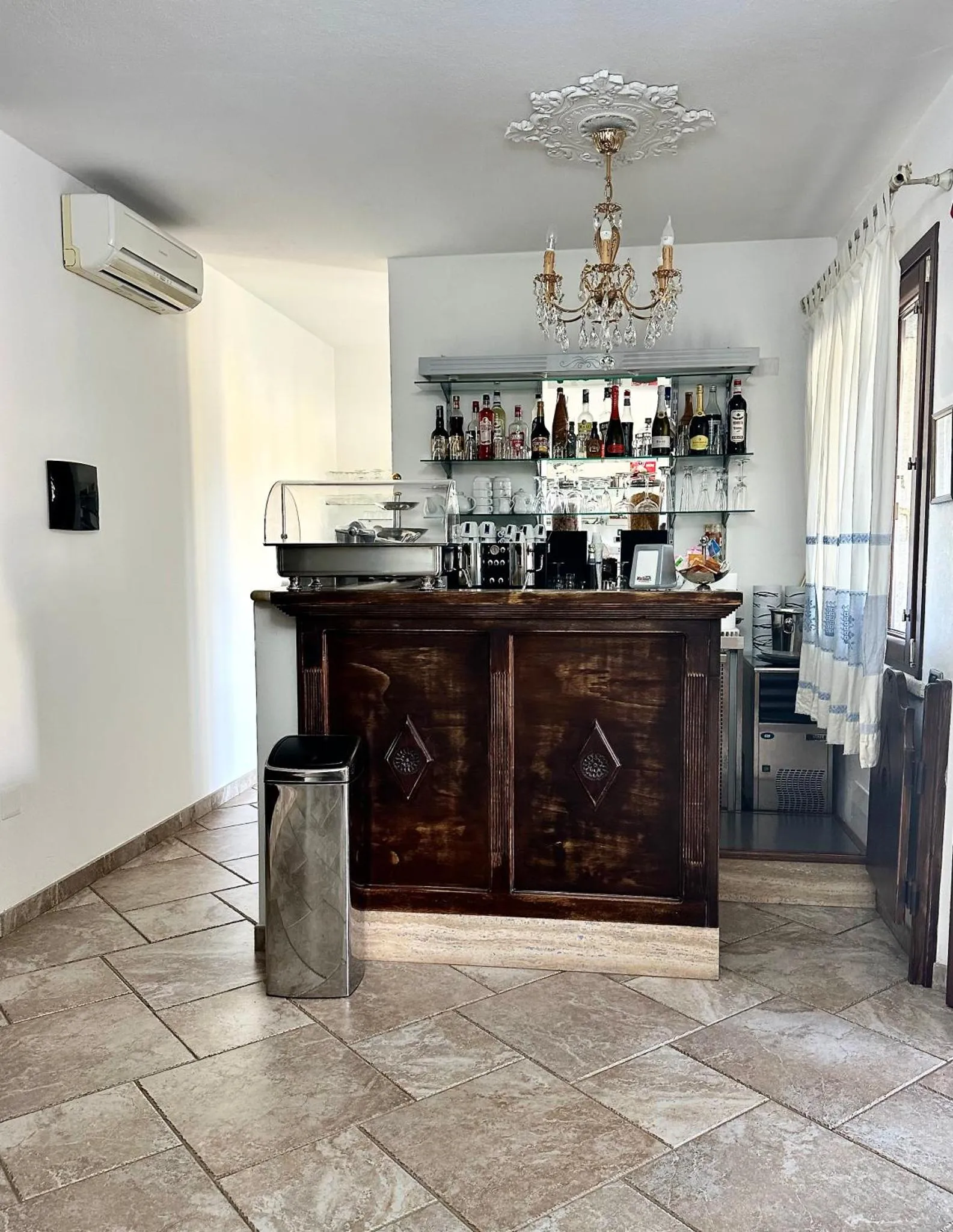 Un comptoir de bar en bois sombre est présenté avec des bouteilles et des verres.
