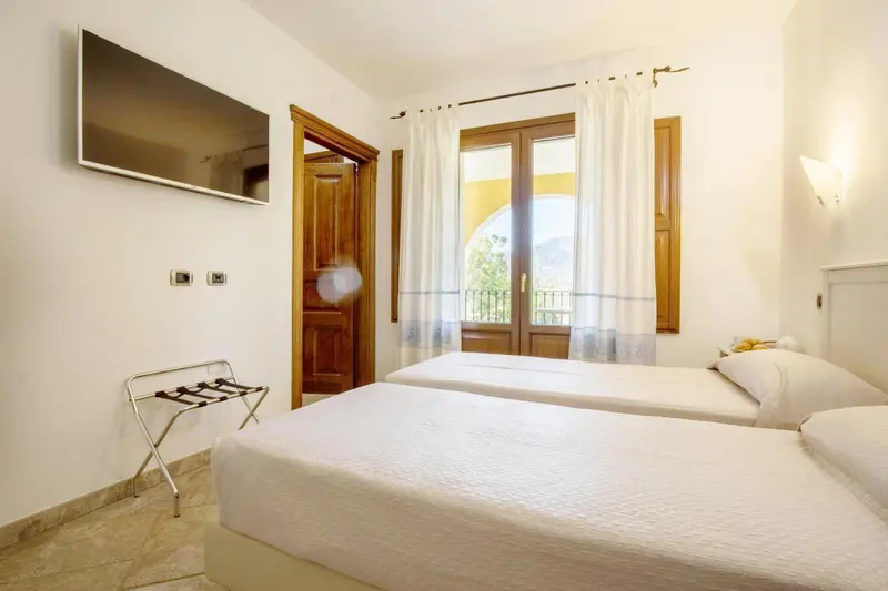 Une chambre lumineuse avec un lit double et une porte-fenêtre donnant sur l'extérieur.