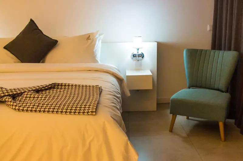 Une chambre lumineuse avec un lit fait et une chaise.