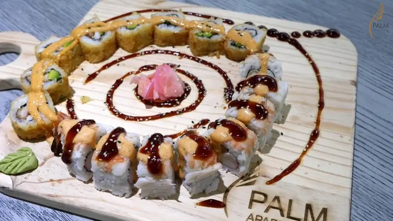 Assiette de sushis présentés en cercle avec une décoration de sauce et de gingembre.