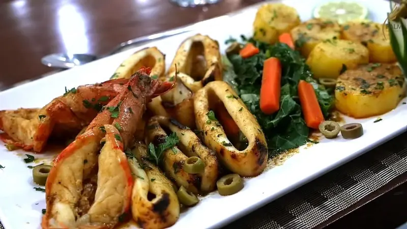 Assiette de fruits de mer grillés avec des légumes et des olives.