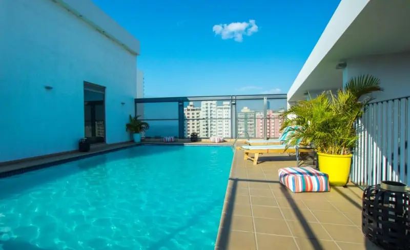 Piscine rectangulaire sur un toit-terrasse ensoleillé avec chaises longues.