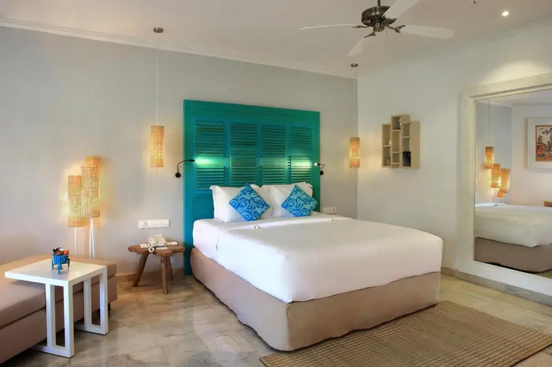 Une chambre lumineuse avec un grand lit et une tête de lit turquoise.