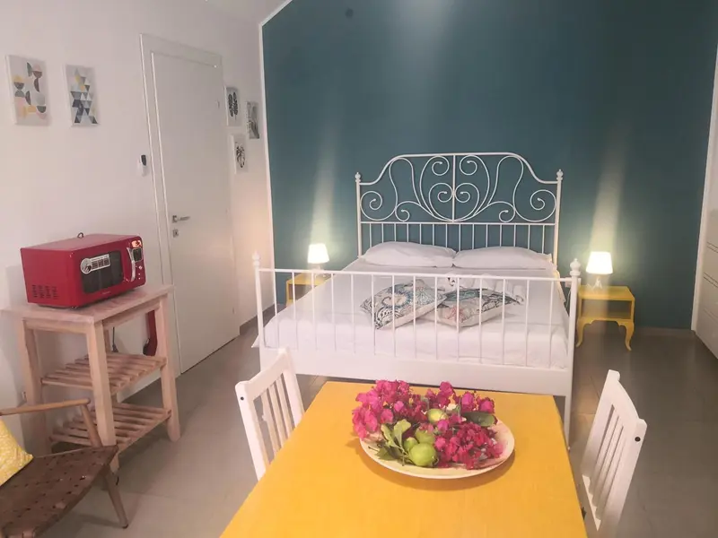 Une chambre lumineuse avec un lit blanc et une table jaune décorée de fleurs.