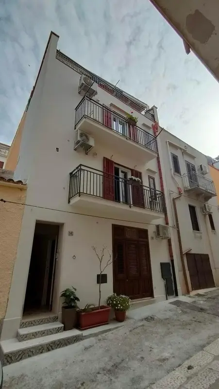Façade d'un bâtiment à plusieurs étages avec des balcons et des volets.
