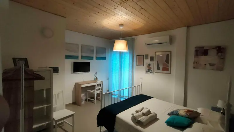 Une chambre lumineuse avec un lit recouvert d'une couverture bleu marine et des tableaux décoratifs.