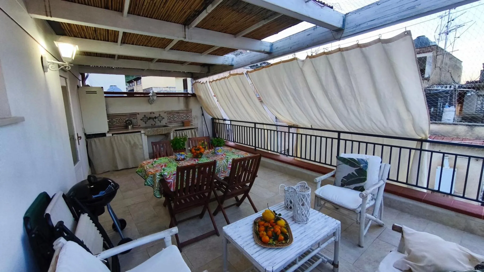 Une table à manger est mise en scène sur une terrasse ombragée.