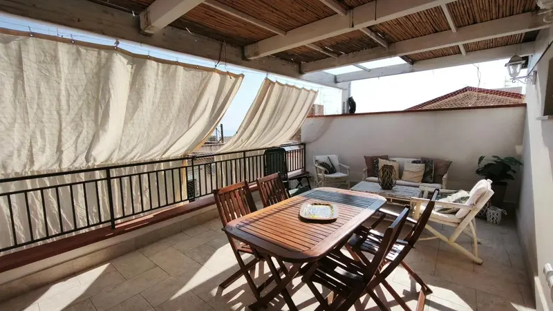 Terrasse ombragée avec mobilier de jardin et table à manger.
