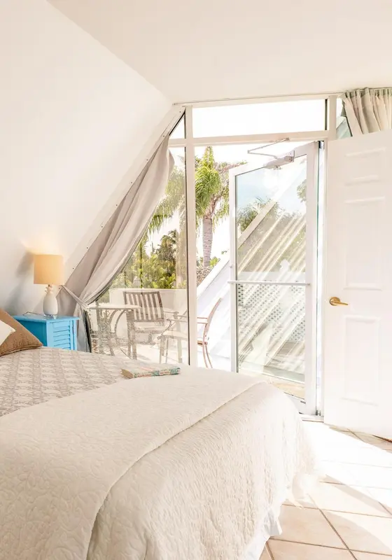 Une chambre lumineuse s'ouvre sur une terrasse ensoleillée.