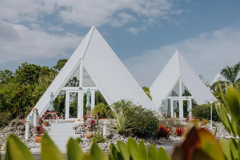 Des bungalows blancs en forme de pyramide se dressent au milieu d'une végétation luxuriante.