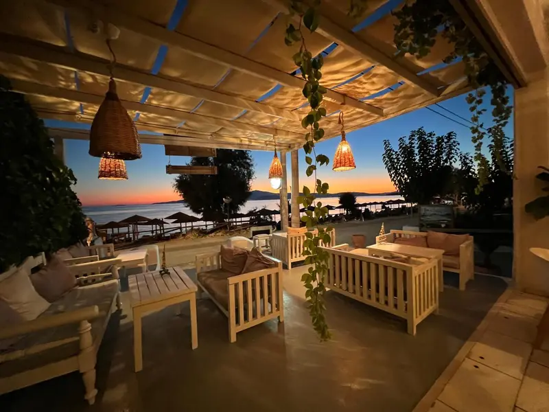 Espace extérieur aménagé avec des meubles blancs et une végétation luxuriante, illuminé par des lampes suspendues.