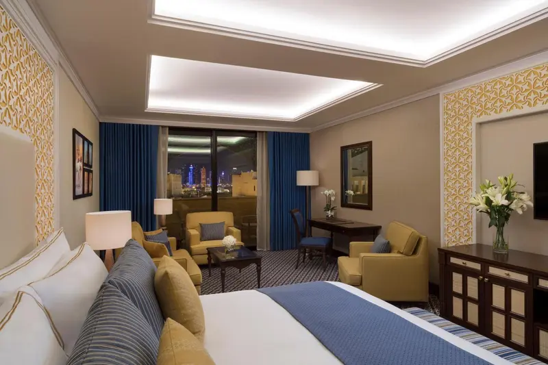 Une chambre lumineuse avec un lit fait et un coin salon.