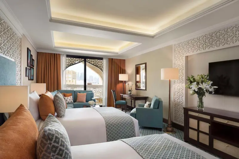Chambre lumineuse avec deux lits et un coin salon.