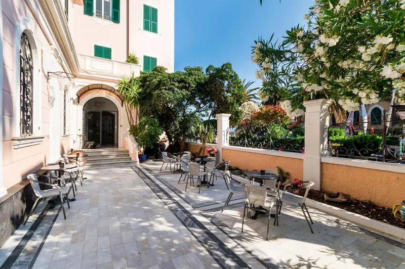 Terrasse pavée avec tables et chaises devant un bâtiment rose.