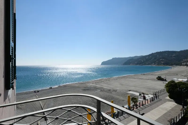 Vue sur la mer et la plage depuis un balcon ensoleillé.