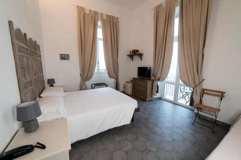 Une chambre lumineuse avec un lit double et un accès à un balcon.