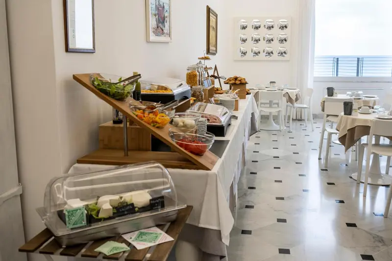 Un buffet propose des viennoiseries, des fruits et des salades dans une salle lumineuse.