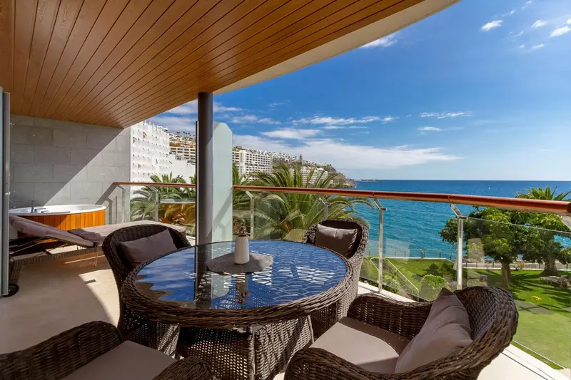 Terrasse aménagée avec mobilier de jardin et vue sur la mer.