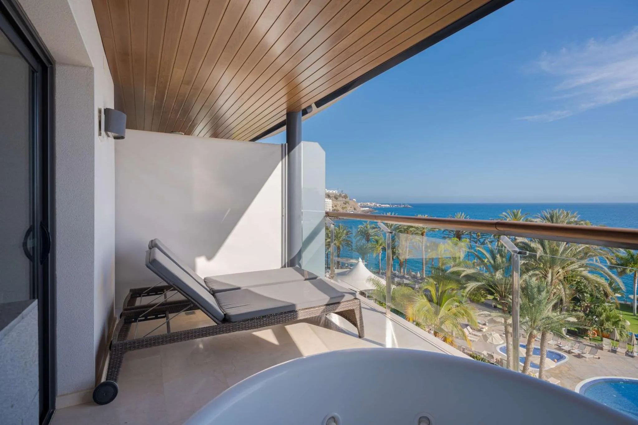 Terrasse avec transats et jacuzzi donnant sur la mer.