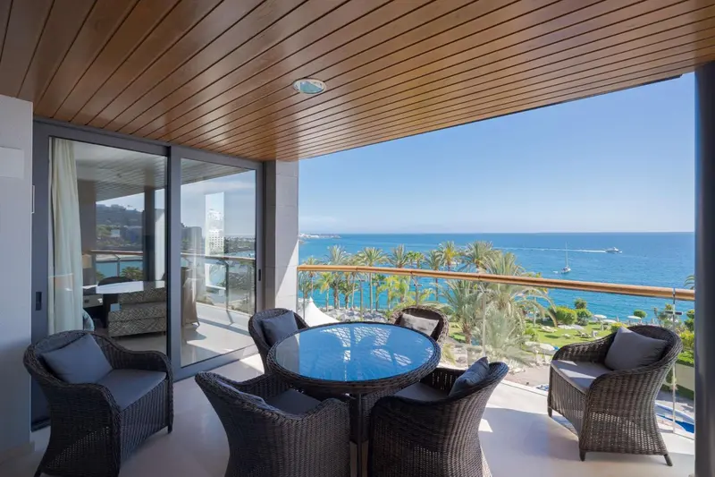 Terrasse aménagée avec table et chaises donnant sur la mer.