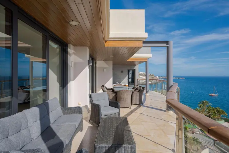 Terrasse aménagée avec canapés et tables basses donnant sur la mer.