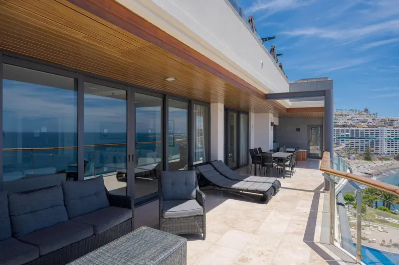 Terrasse aménagée avec salon et chaises longues donnant sur la mer.