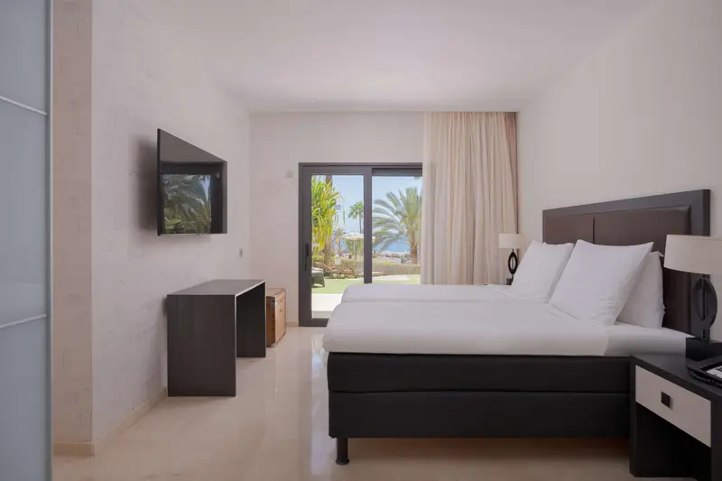 Une chambre lumineuse avec un grand lit et une vue sur un jardin tropical.
