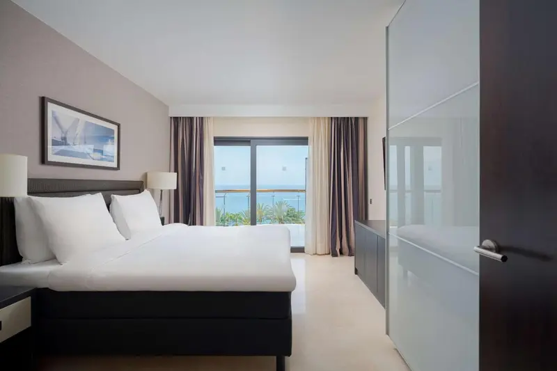 Une chambre lumineuse avec un grand lit et une vue sur la mer.