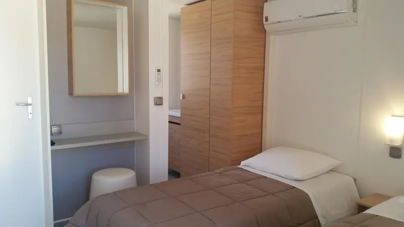Une chambre sobre avec un lit simple et un miroir mural.