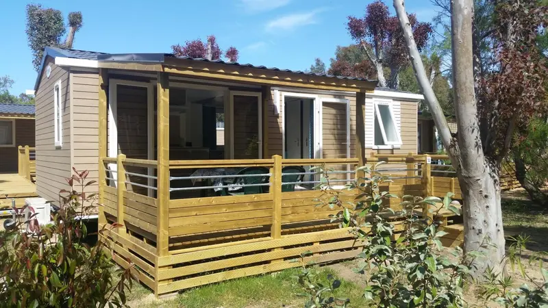 Mobil-home en bois avec terrasse et garde-corps.