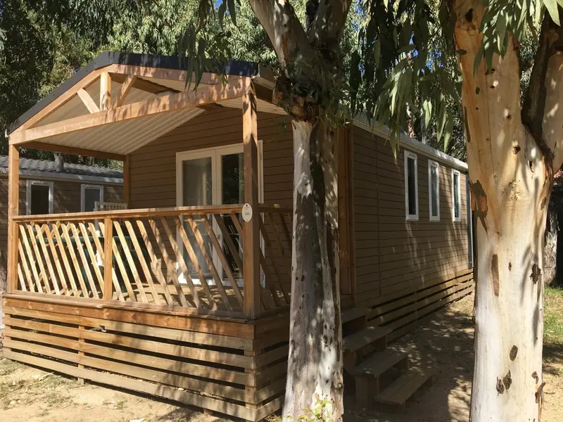 Mobil-home en bois avec terrasse et garde-corps.
