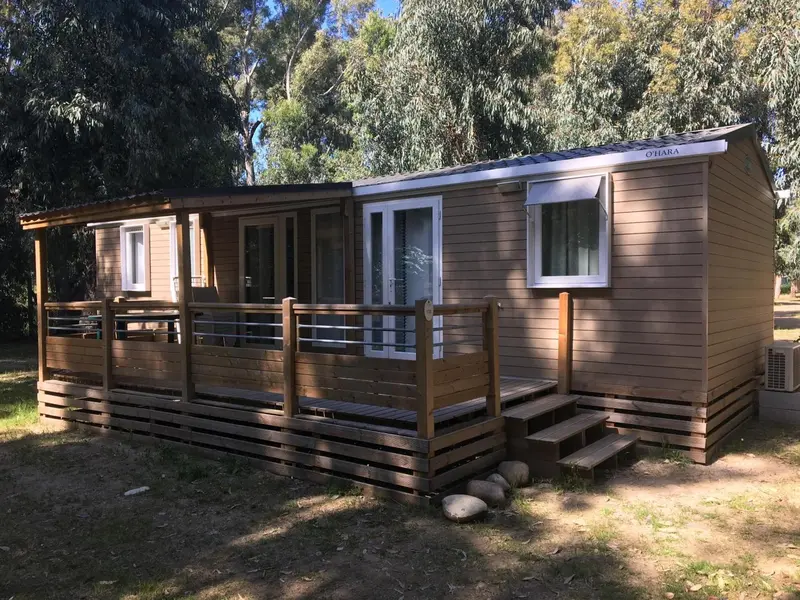 Mobil-home en bois avec terrasse et escaliers.