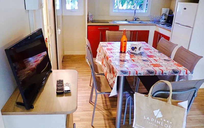 Une table et des chaises se trouvent devant une kitchenette dans un intérieur lumineux.