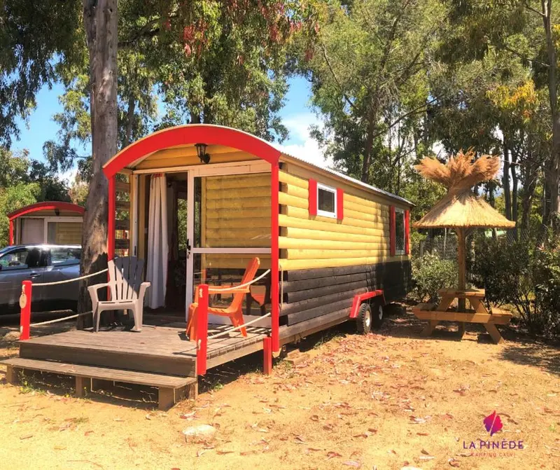 Une petite cabane en bois colorée avec une terrasse et du mobilier de jardin.