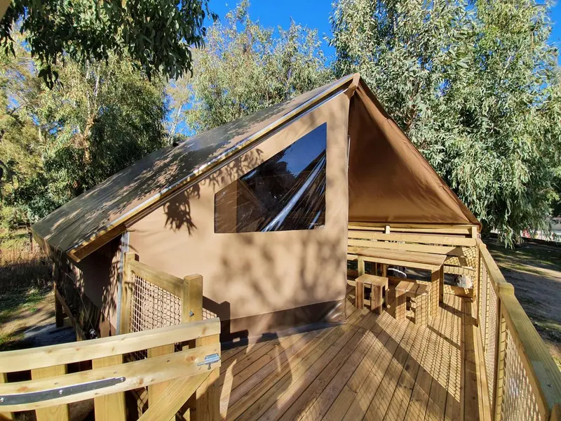 Tente aménagée sur une terrasse en bois avec garde-corps.