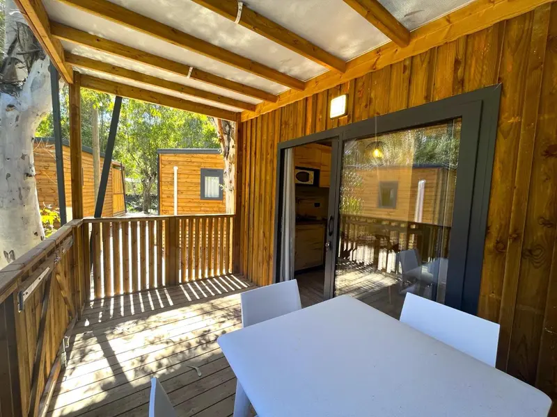 Terrasse en bois avec table et chaises devant une porte vitrée.