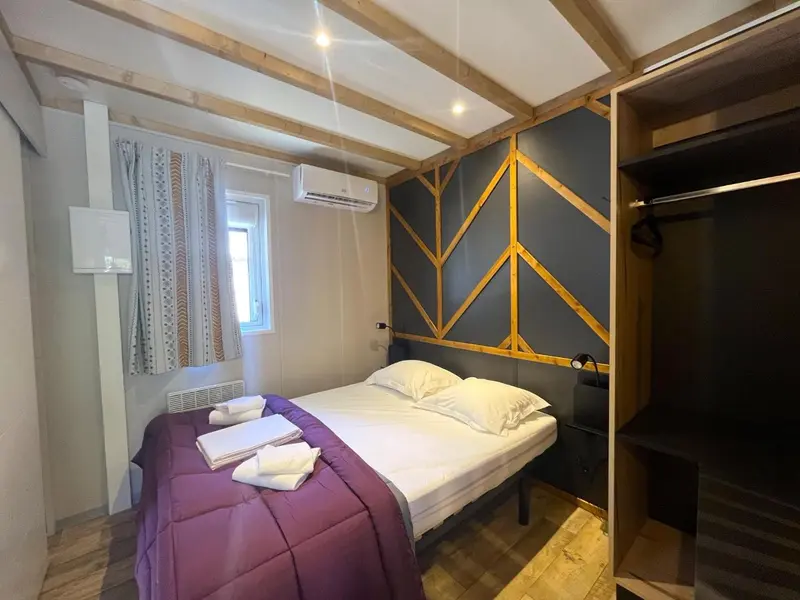 Une chambre avec un lit recouvert d'une couverture violette et de serviettes.