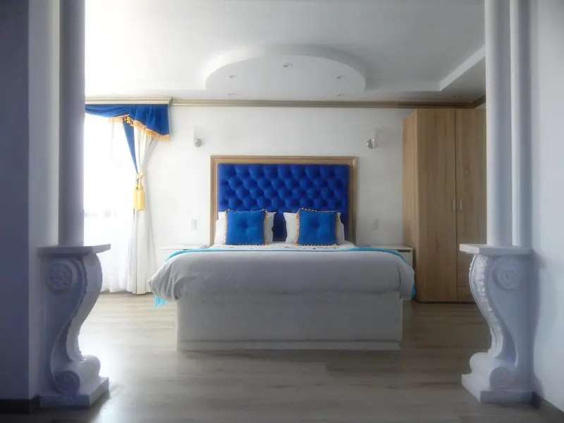 Une chambre lumineuse avec un grand lit recouvert de blanc et de bleu.