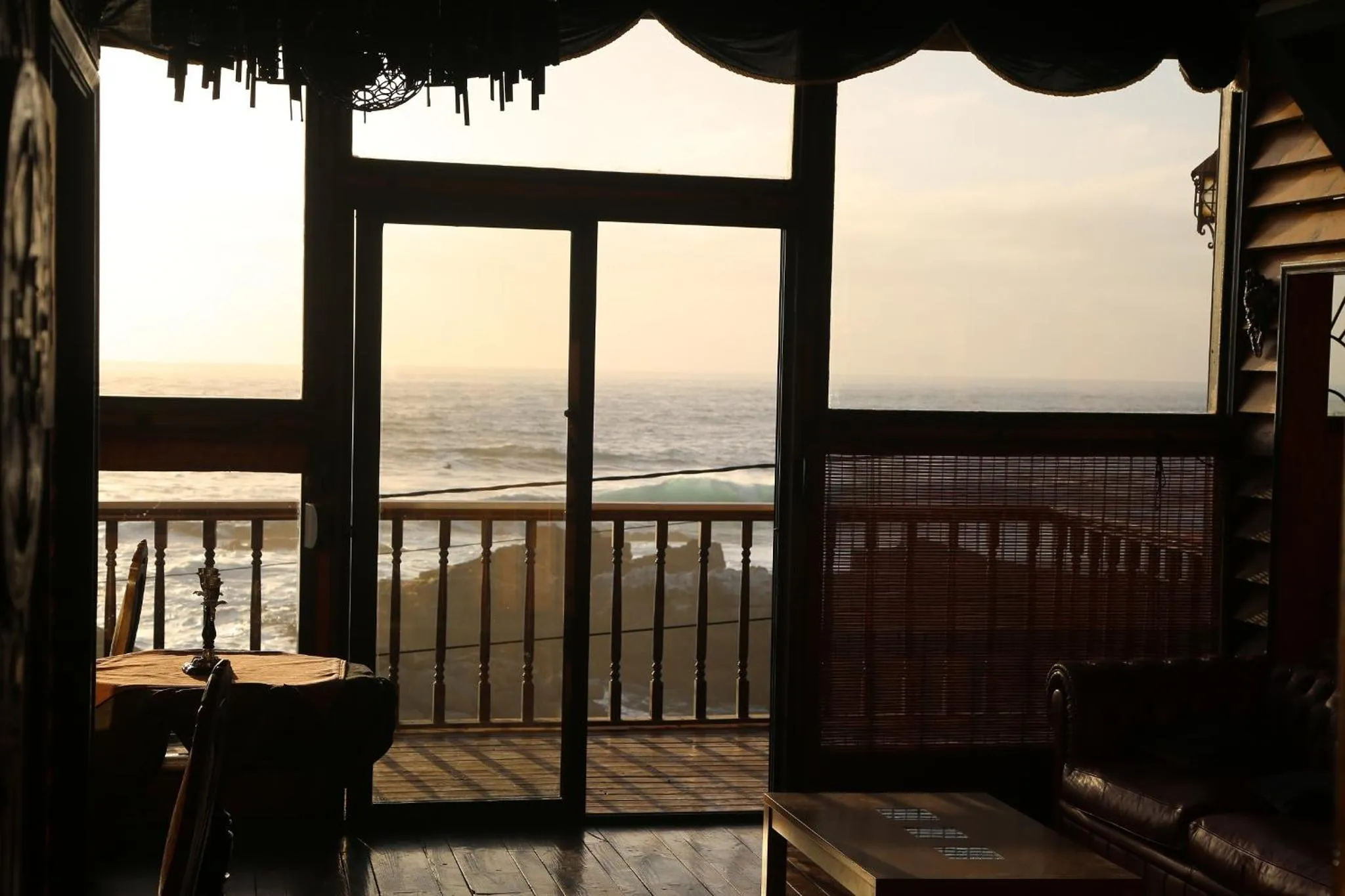 Vue sur la mer depuis une terrasse ombragée avec mobilier.